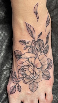 a black and white tattoo of a rose on the foot