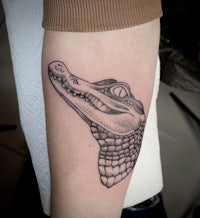a tattoo of a crocodile on the forearm