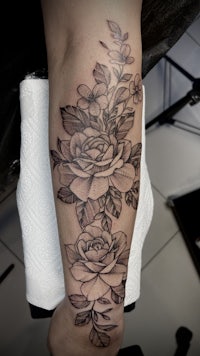 a black and white rose tattoo on the forearm