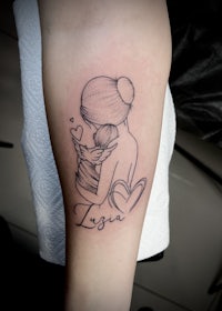 a tattoo of a woman with a baby in her arms