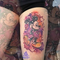 a tattoo of mickey mouse on the thigh