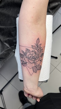 a black and white tattoo of a rose on the forearm