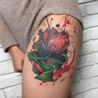 a tattoo of a red tulip on a woman's thigh