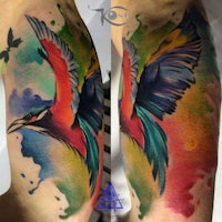 a colorful tattoo of a bird on the forearm
